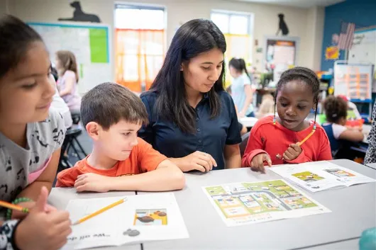 Volunteer working with three students